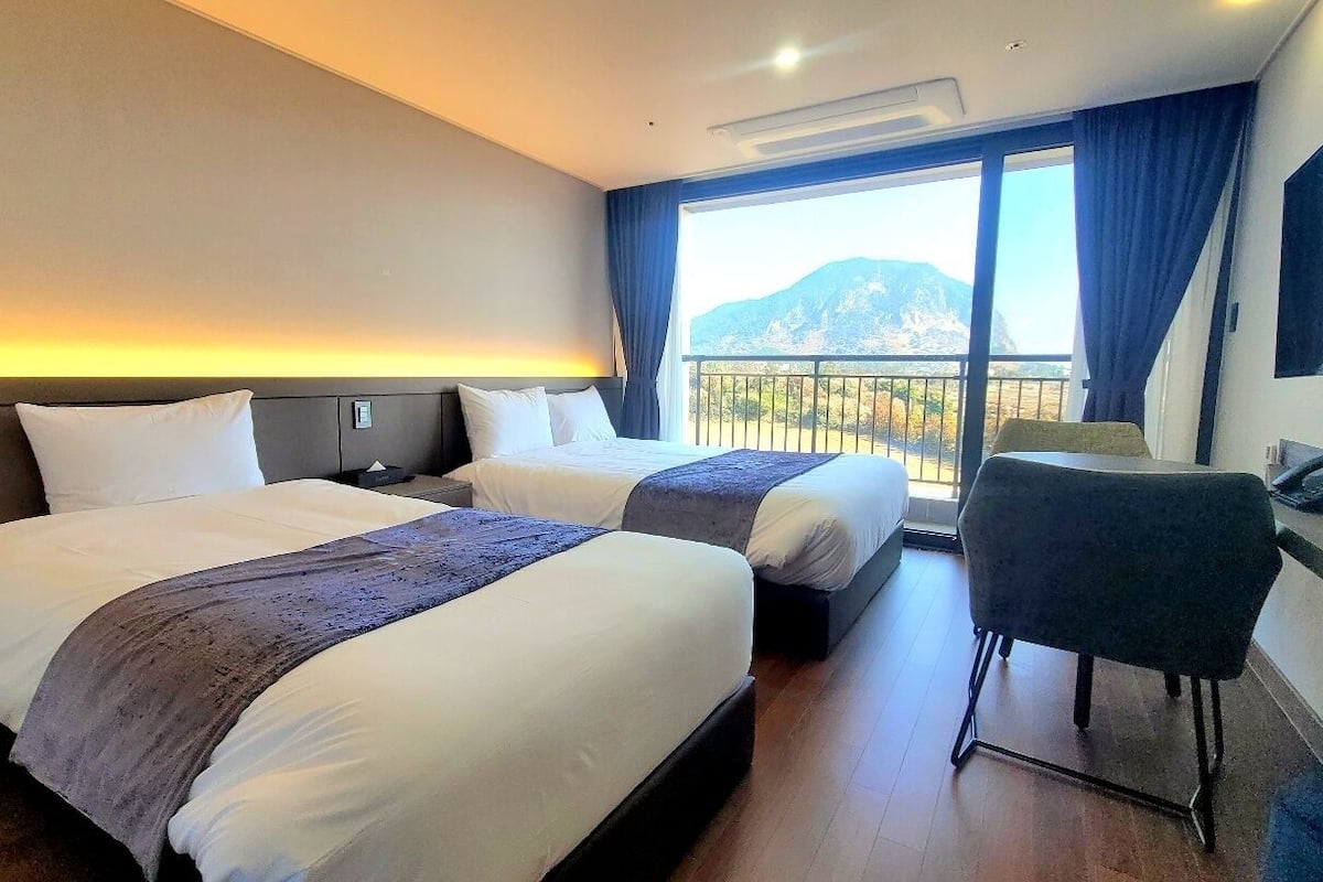 Une chambre d’hôtel avec deux lits, un bureau et une chaise.