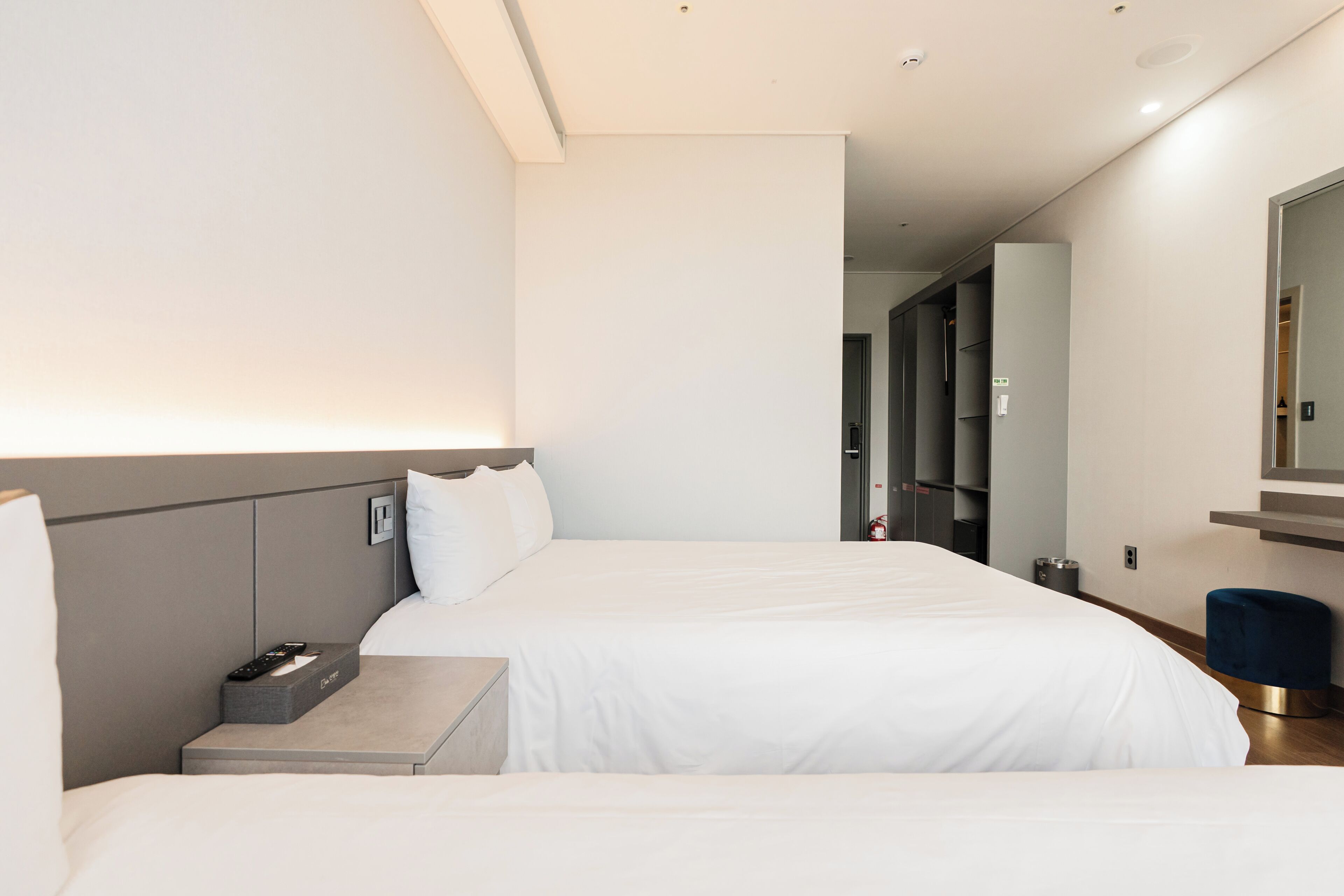 A modern hotel room with a large bed, bedside tables, a mirror, and a wardrobe.