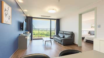 A modern hotel room with a balcony, a sofa, a desk with a telephone, and a bed.