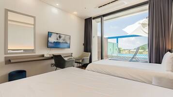A hotel room with two beds, a desk, a chair, a TV, and a large window with a view of a pool and mountains.