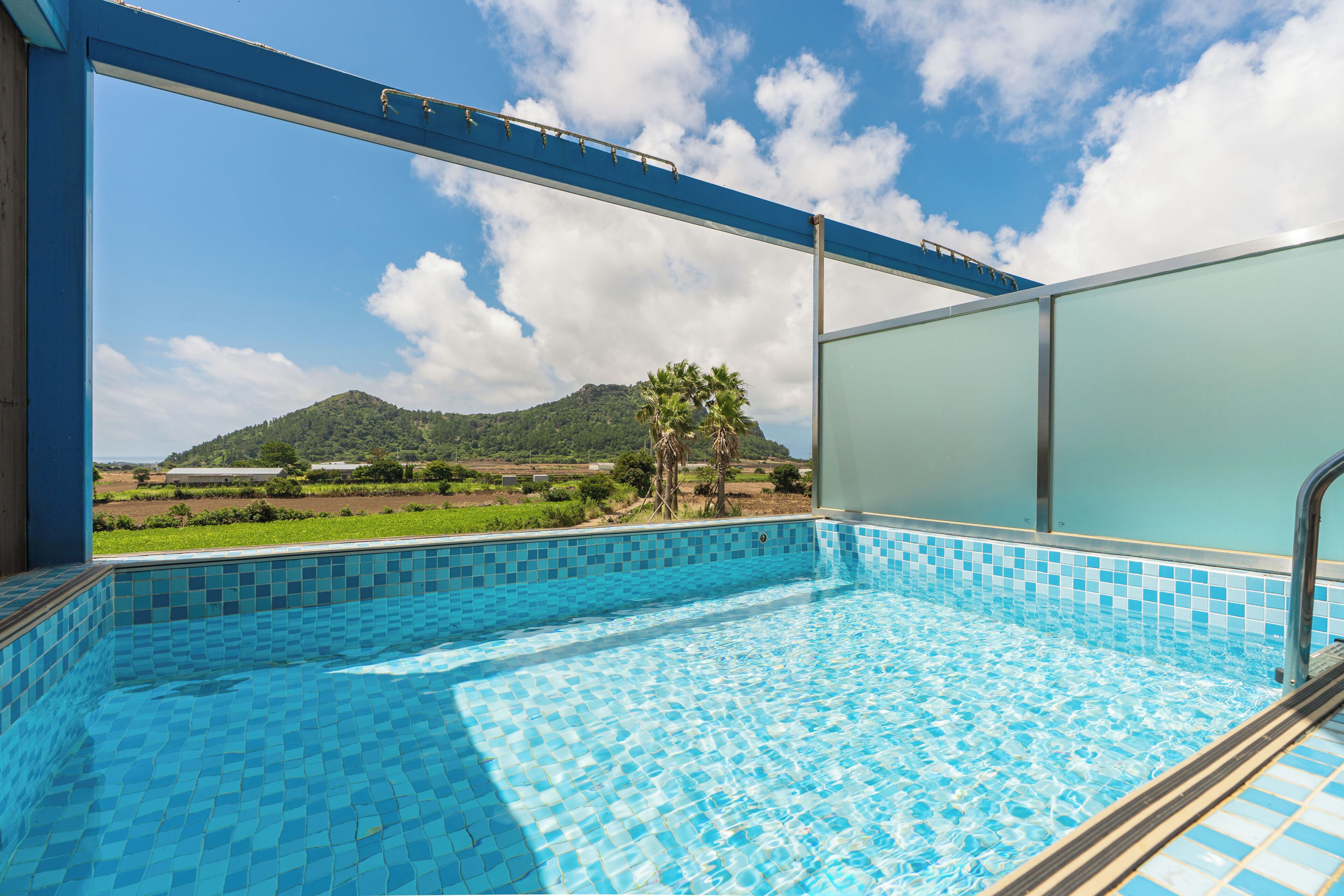 Piscina com vista para uma montanha e palmeiras.
