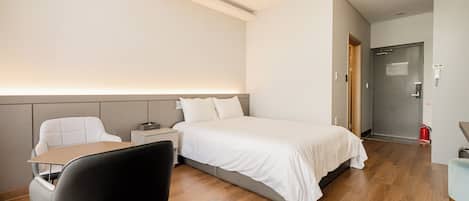 Una habitación de hotel con cama, mesita de noche, silla y escritorio.