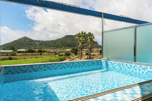 A swimming pool with a view of a mountain and palm trees. - Sanbangsan Hotel (Seogwipo)