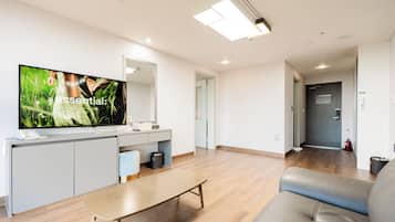 Een moderne woonkamer met een flatscreen-tv, een bank, een salontafel en een keuken met een aanrecht en kasten.