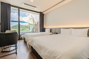 Een hotelkamer met twee bedden, een stoel, een bureau en uitzicht op het groen.