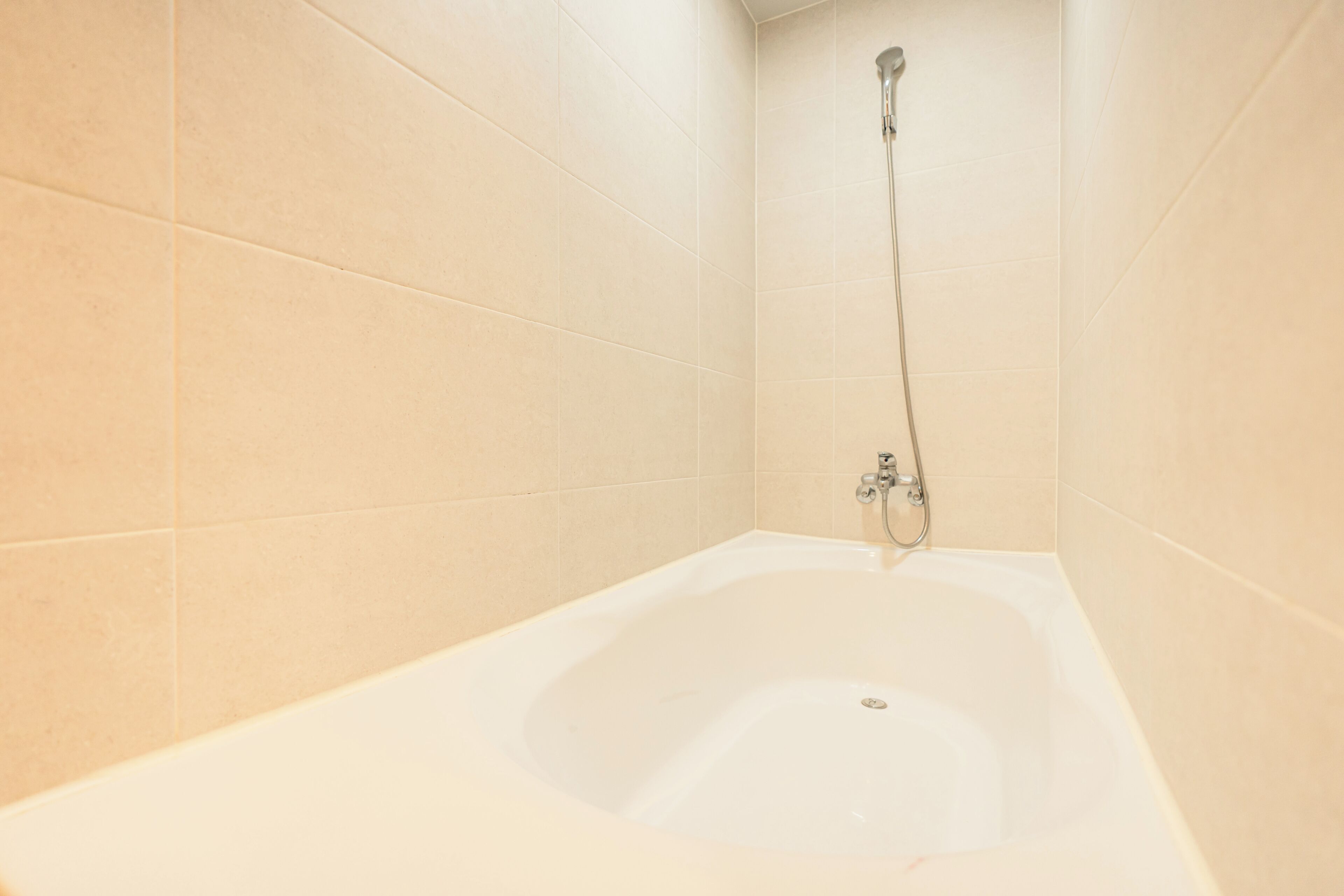Un baño con bañera, ducha y paredes de azulejos.