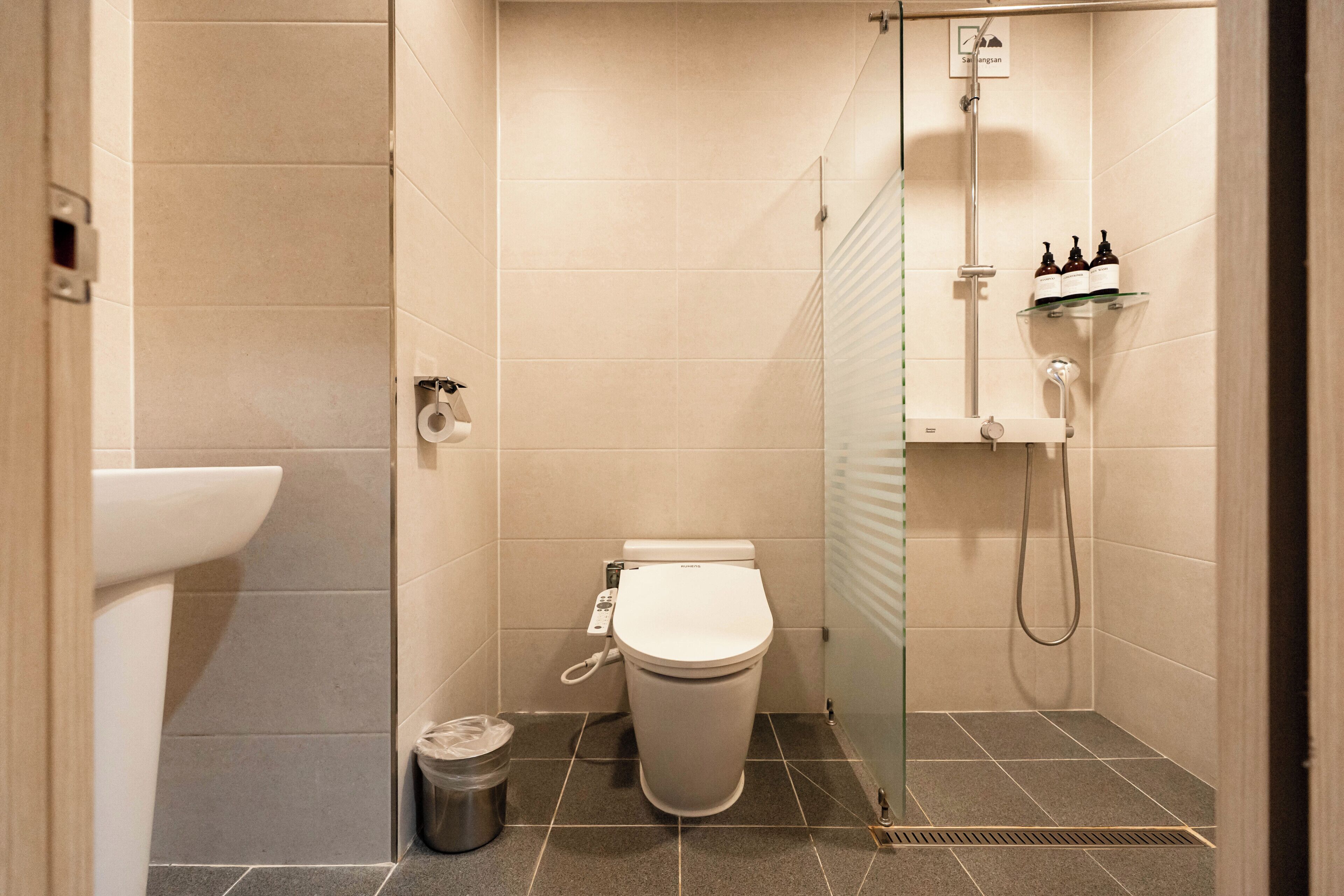 A modern bathroom with a toilet, a glass shower enclosure, and a sink.