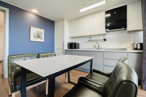 A compact kitchen with white cabinets, a black microwave, and a coffee maker. - Sanbangsan Hotel (Seogwipo)