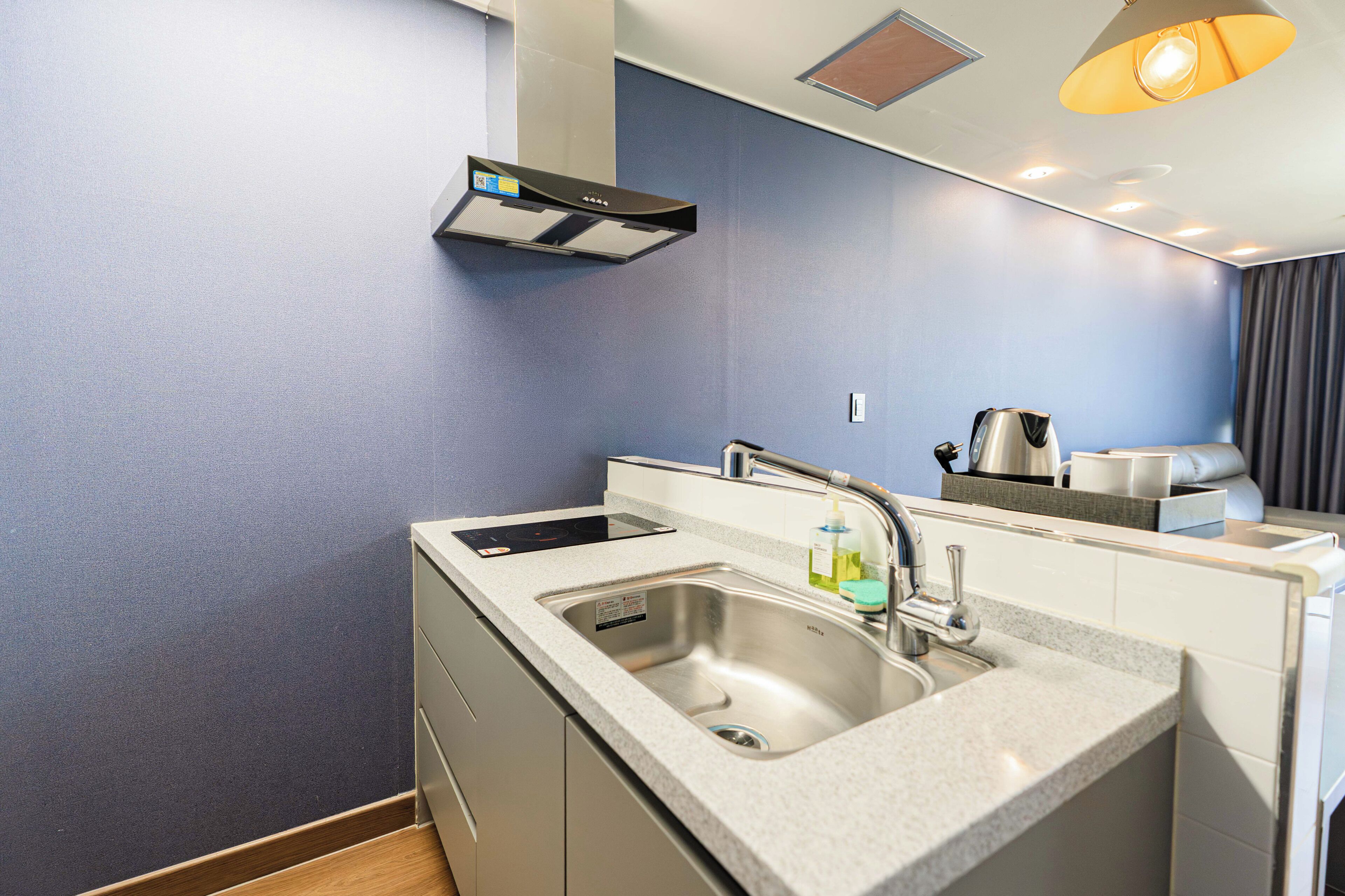 A modern kitchen with a built-in stove, a sink, and a kettle.