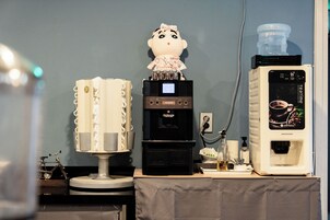 Una cafetera, un dispensador de agua y un objeto decorativo sobre una mesa.