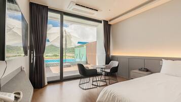 Ein Hotelzimmer mit Bett, Schreibtisch, Stuhl, Telefon und Blick auf Pool und Berge.