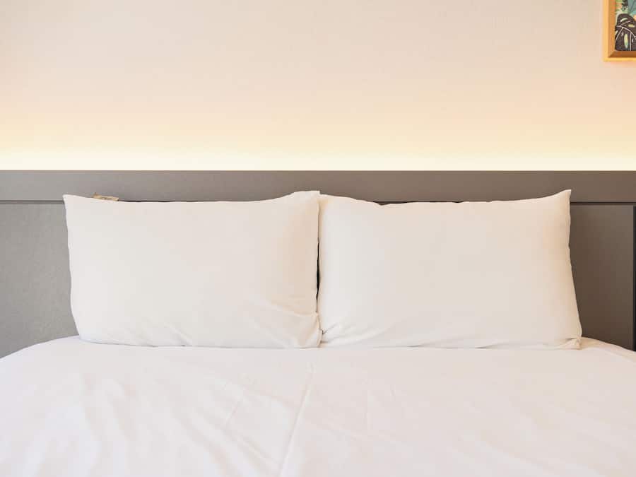 Een bed met een grijze hoofdbord en witte beddengoed.