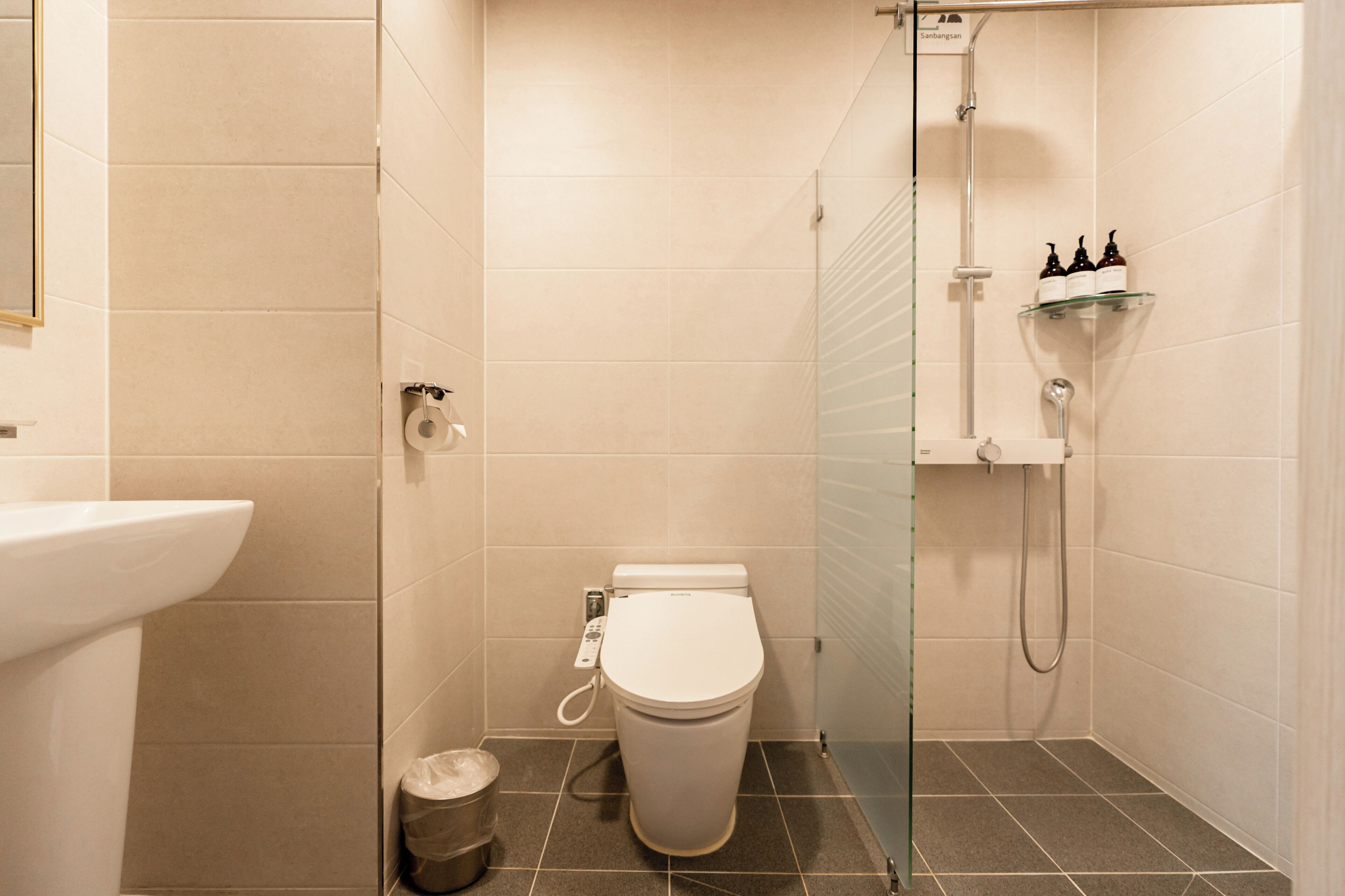 A modern bathroom with a toilet, bidet, and glass shower enclosure.