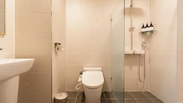 A modern bathroom with a toilet, bidet, and glass shower enclosure.