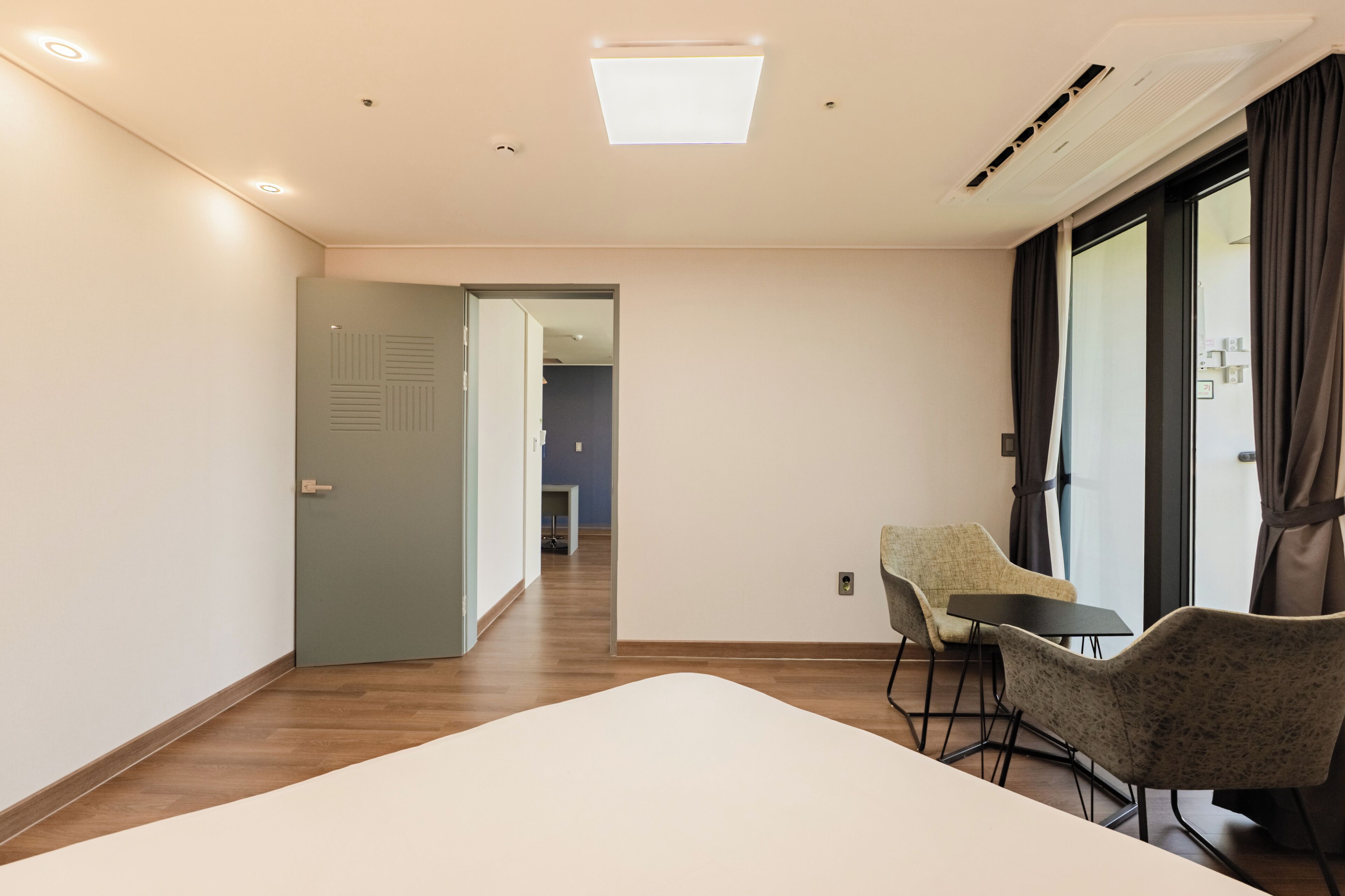 Une chambre d’hôtel avec un lit, une chaise, une table et une vue sur le couloir.