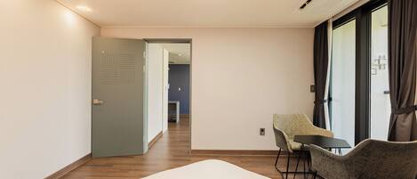Une chambre d’hôtel avec un lit, une chaise, une table et une vue sur le couloir.