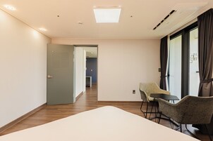 Habitación de hotel con cama, una silla, una mesa y vista al pasillo.