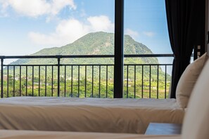 A bed with a view of a mountain through a balcony railing. - Sanbangsan Hotel (Seogwipo)