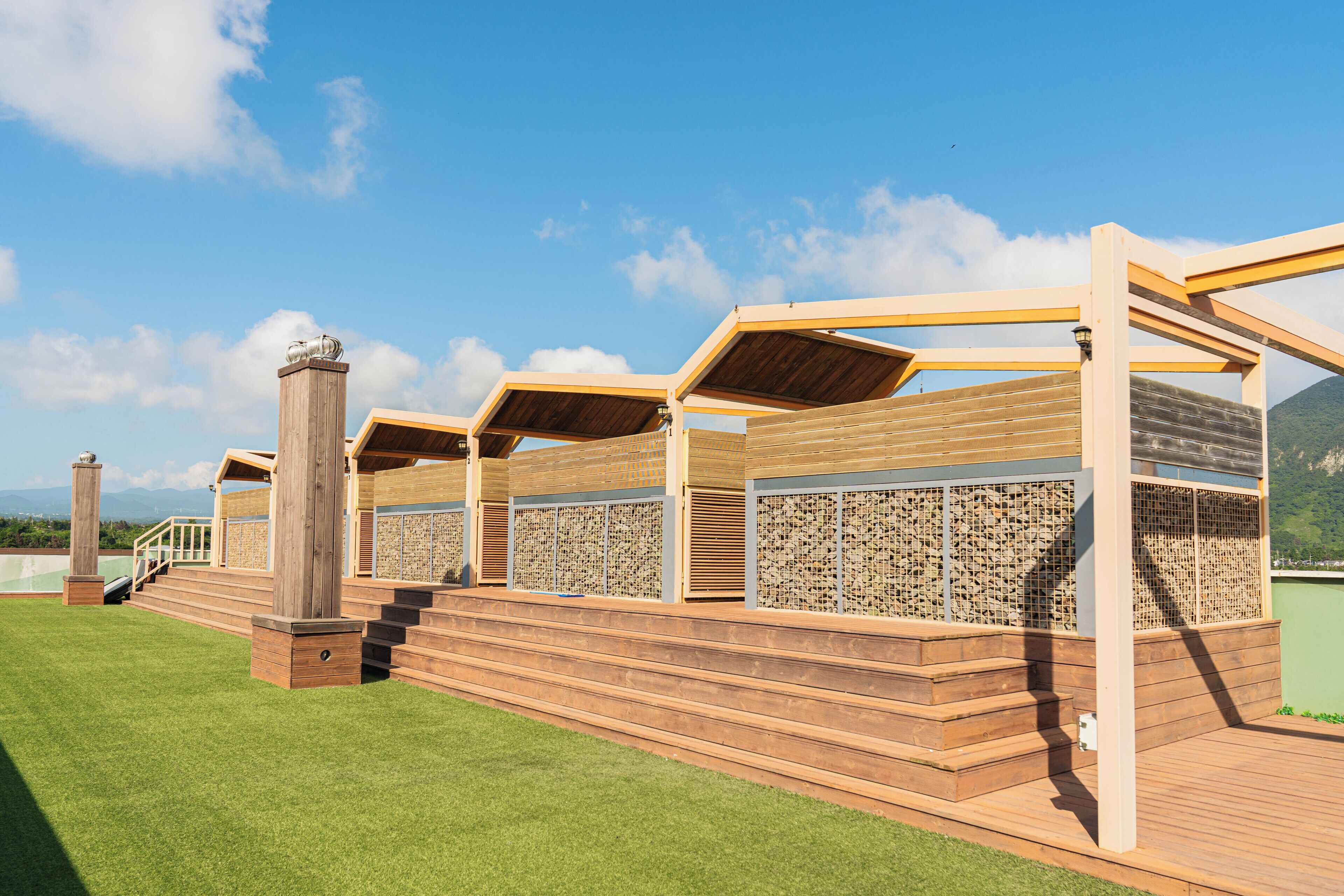 A wooden deck with a pergola structure, a staircase, and a view of a mountain range.