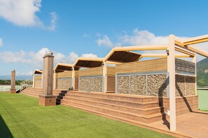 Eine Holzterrasse mit einer Pergola, einer Treppe und Blick auf ein Gebirge.