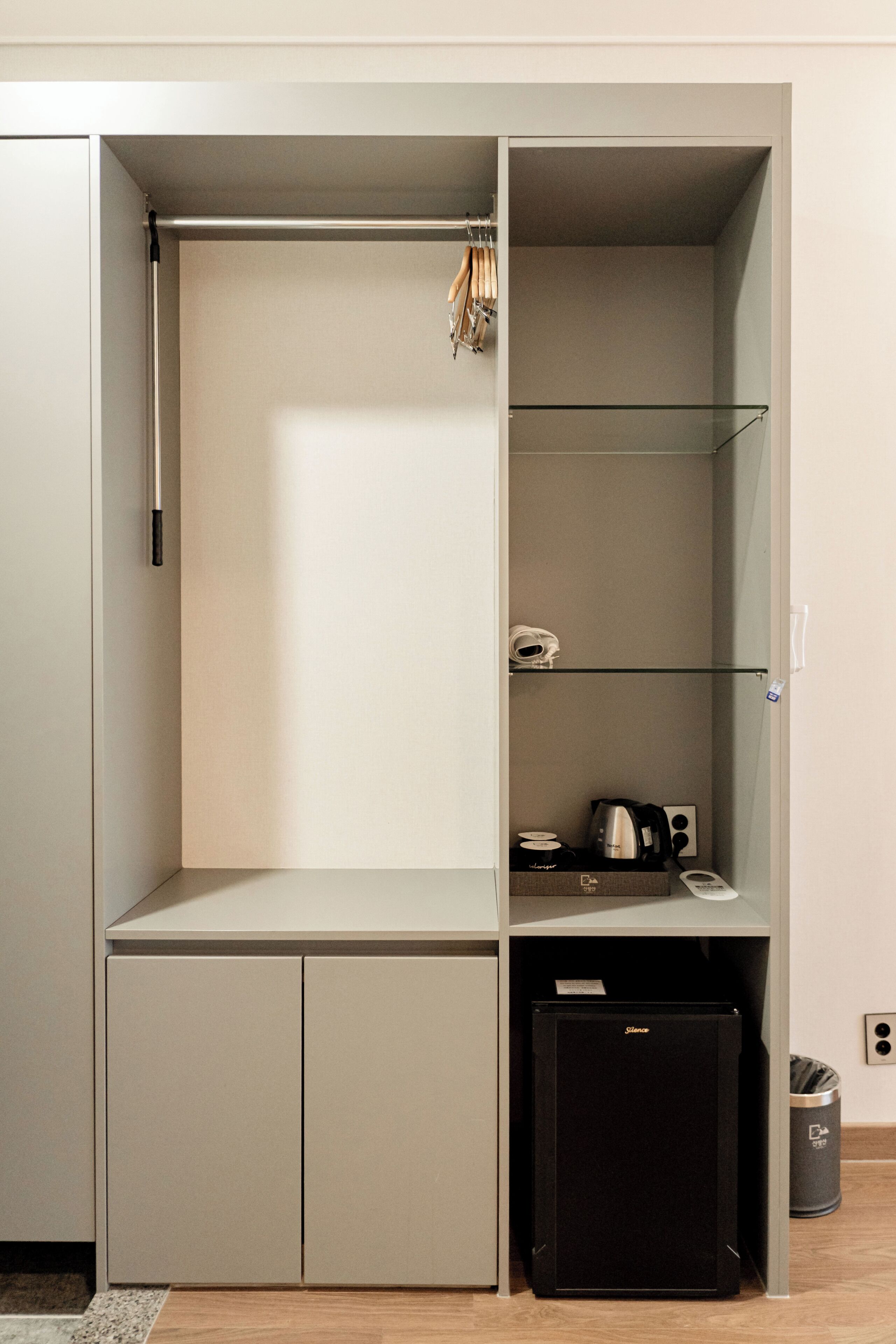 A compact storage unit with a pull-out shelf, a small refrigerator, and a trash bin.