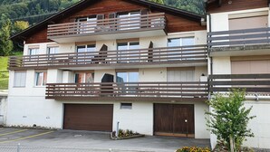 A multi-story building with balconies, a garage, and a parking area. - Elfe Apartments Studio for 2 Adults, Balcony With Lake and Mountain View (Emmetten)