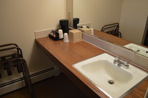 Un baño con tocador de madera, un lavabo blanco, un espejo y un perchero para toallas.