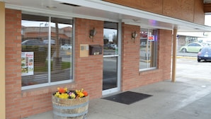 A storefront with a brick facade, large windows, and a wooden barrel filled with flowers. - Rodeway Inn Cody (Cody)