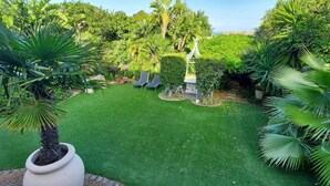 A lush garden with a well-maintained lawn, various tropical plants, and a seating area with chairs. - Room in Apartment - The Garden Apartment - Roosboom Luxury Facilities in Somerset West, 2 Guests (Cape Town)