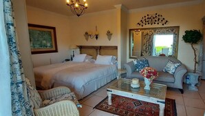 A bedroom with a large bed, a sofa, a coffee table with a vase, and a mirror. - Room in Apartment - The Garden Apartment - Roosboom Luxury Facilities in Somerset West, 2 Guests (Cape Town)