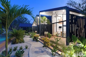 Une maison moderne dotée d’une piscine, d’un espace salon extérieur et de plantes tropicales.