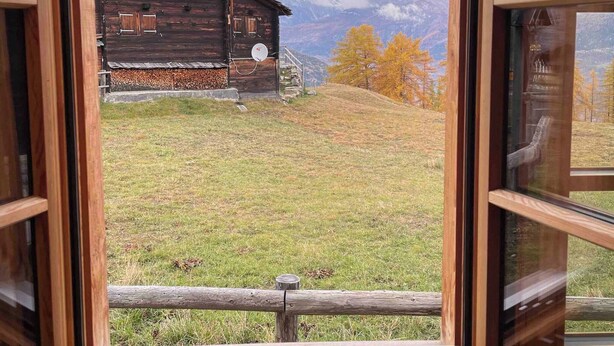A wooden cabin with a view of mountains and autumn foliage through a window. - Appartement for Holiday Lodge 1891 (Stalden)