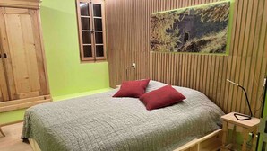 A bedroom with a bed, a wooden wardrobe, a window, and a wall-mounted picture. - Appartement for Holiday Lodge 1891 (Stalden)