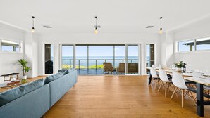 Une pièce spacieuse avec une grande table à manger, un canapé et une vue sur l’océan.