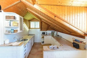 A kitchen with a wooden ceiling, white cabinets, a microwave, and a sink. - Charming 2-bedroom Apartment With Ocean Views in Dubrovnik (Dubrovnik)