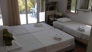Een hotelkamer met twee bedden, een tafeltje, een stoel en een boekenkast.