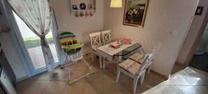 A dining area with a table, chairs, and a colorful children's potty chair. - Palm Garden Apartment (Sithonia)