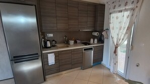 Een moderne keuken met roestvrijstalen apparatuur, houten keukenkastjes en een raam met gordijnen.