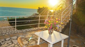 A patio with a table and chairs, a vase of flowers, and a view of the sea. - Studio Apartments Maria With Pool and Amazing View - Agios Gordios Beach (Corfu)