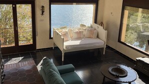 A spacious living room with a large bed, a sofa, and a coffee table. There are two windows providing views of the outdoors. - "Roc del amor" Villa first line sea pool (Roses)