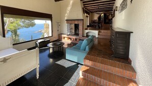 A spacious living area with a fireplace, a sofa, and a view of the sea. - "Roc del amor" Villa first line sea pool (Roses)