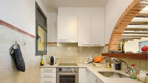 A compact kitchen with white cabinets, a built-in oven, a sink, and a brick archway. - "Roc del amor" Villa first line sea pool (Roses)