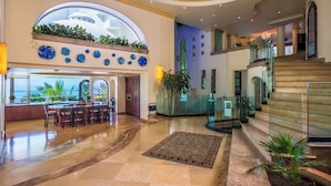 A spacious lobby with a large seating area, a staircase, and a view of the ocean. - Beach Frontage Armonia Villa With Stunning Views (Puerto Vallarta)
