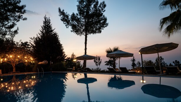 A poolside area with lounge chairs and umbrellas, surrounded by trees and a clear sky. - Olympos Mountain Lodge (Kemer)