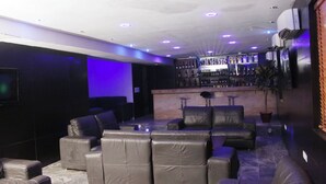 A modern bar area with leather sofas, a bar counter with bottles, and a flat-screen TV mounted on the wall. - Room-royalrex Hotel-guest Suite (Lagos)
