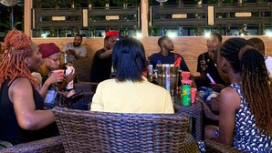 An outdoor seating area with wicker chairs and tables, hanging lights, and a wooden ceiling. - Room-aerol Hotel and Suites -super Suite (Lagos)