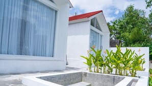 A modern house with large windows, a red roof, and a concrete garden area. - Jempana View (Kintamani)