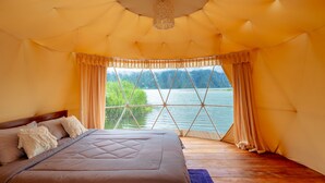 A bedroom with a large bed, a view of a lake, and a ceiling with a hanging light fixture. - Jempana View (Kintamani)