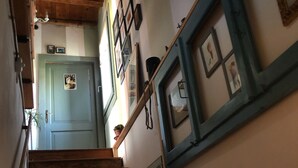 A wooden staircase with a handrail, a light blue door at the top, and framed pictures on the walls. - Room in B&B - B&b Carlonga A Double Room For Two People (Caneva)