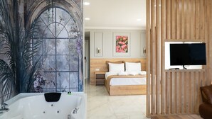 A bedroom with a large bed, a TV, and a bathroom with a bathtub.